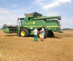 Konstruktyvus ūkininko ir DOJUS agro specialisto pokalbis šalia demonstruojamo kombaino 